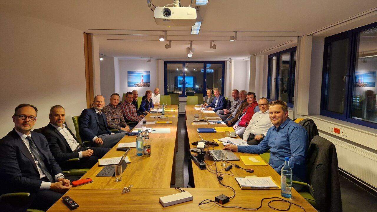 Zahlreiche Personen sitzen an einem Konferenztisch