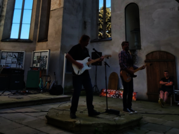 Rock und Lyrik Zwei Männer spielen Gitarre in einer Kirche ohne Dach