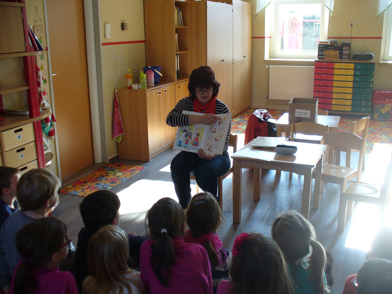 KEB Veranstaltung in Oschatz Dunkelhaarige Frau zeigt Kindern Buch in einer Bibliothek