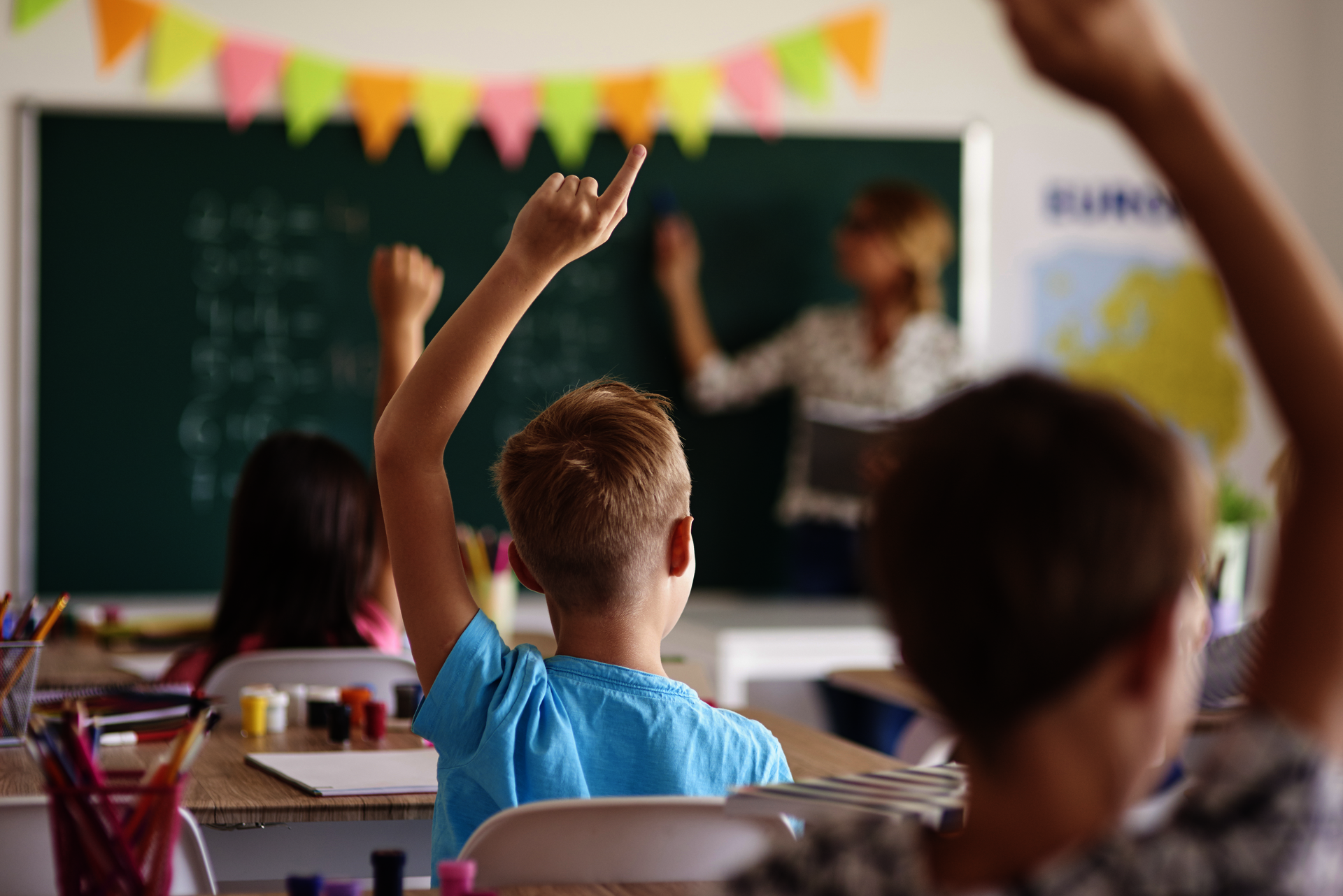 Foto: iStock.com / gpointstudio Kinder in einem Klassenzimmer, die sich mit Handzeichen melden