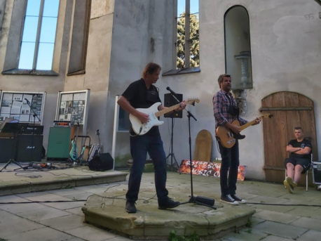 Rock und Lyrik Zwei Männer spielen Gitarre in einer Kirche ohne Dach